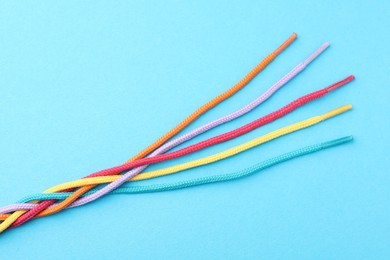 Photo of Braided colorful ropes on light blue background, top view. Unity concept