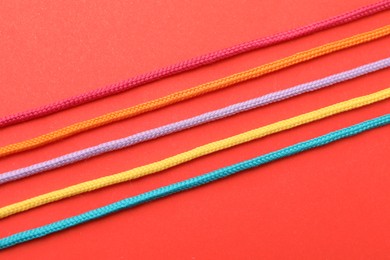 Photo of Colorful ropes on red background, top view. Unity concept