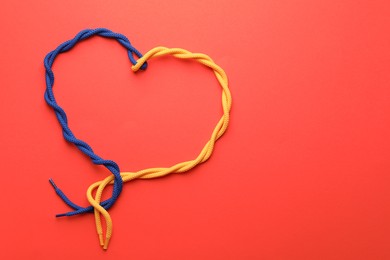 Photo of Heart made of tied ropes on red background, top view with space for text. Unity concept