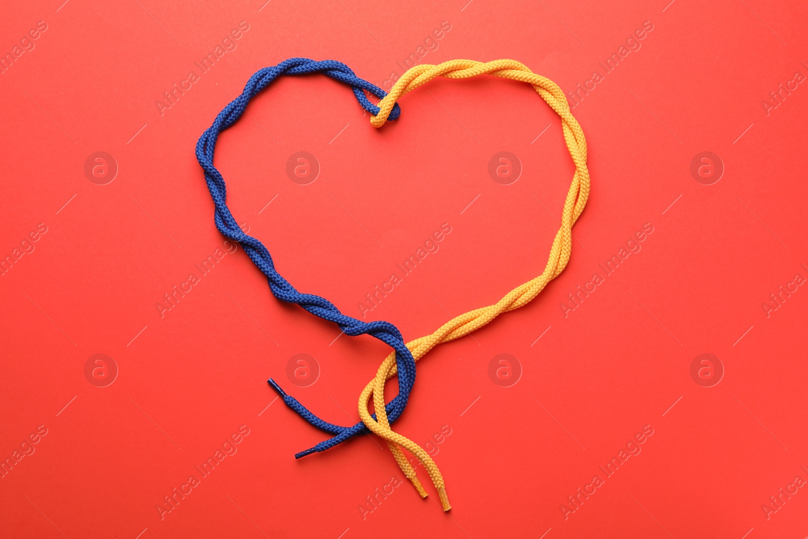 Photo of Heart made of tied ropes on red background, top view. Unity concept