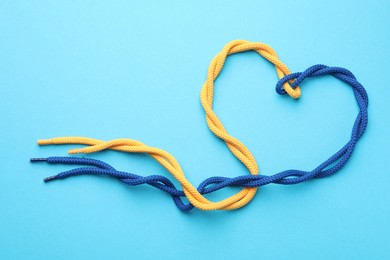 Photo of Heart made of tied ropes on light blue background, top view. Unity concept