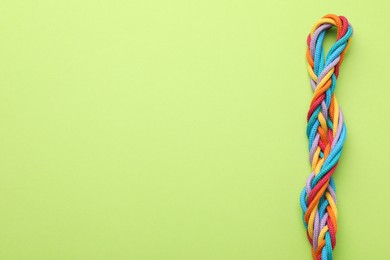 Photo of Braided colorful ropes on light green background, top view with space for text. Unity concept