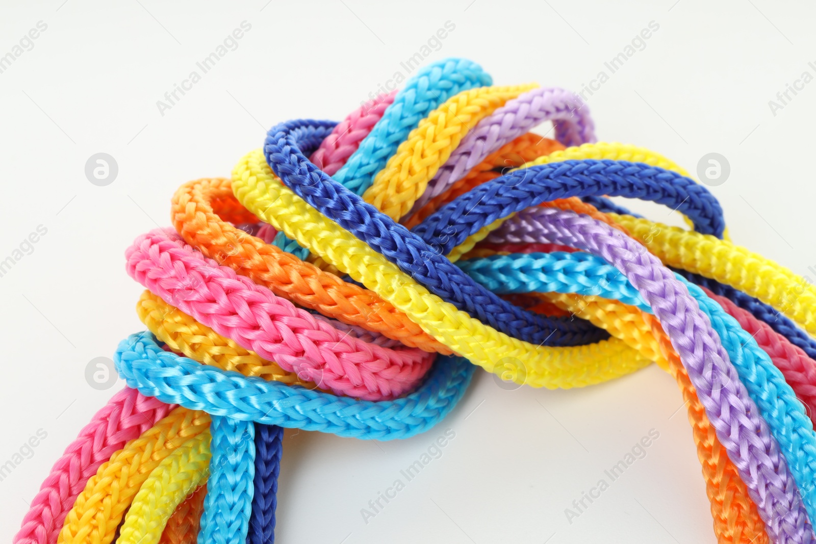 Photo of Colorful ropes tied in knot on white background, closeup. Unity concept