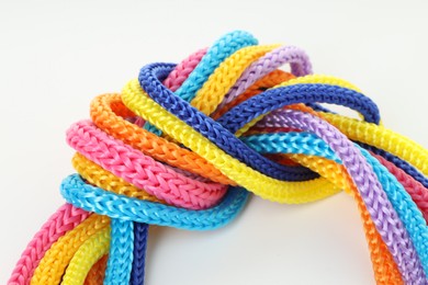 Photo of Colorful ropes tied in knot on white background, closeup. Unity concept