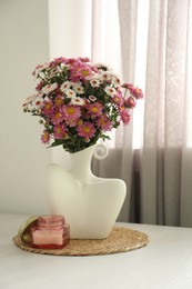 Photo of Stylish vase with beautiful flowers and candle on white wooden table