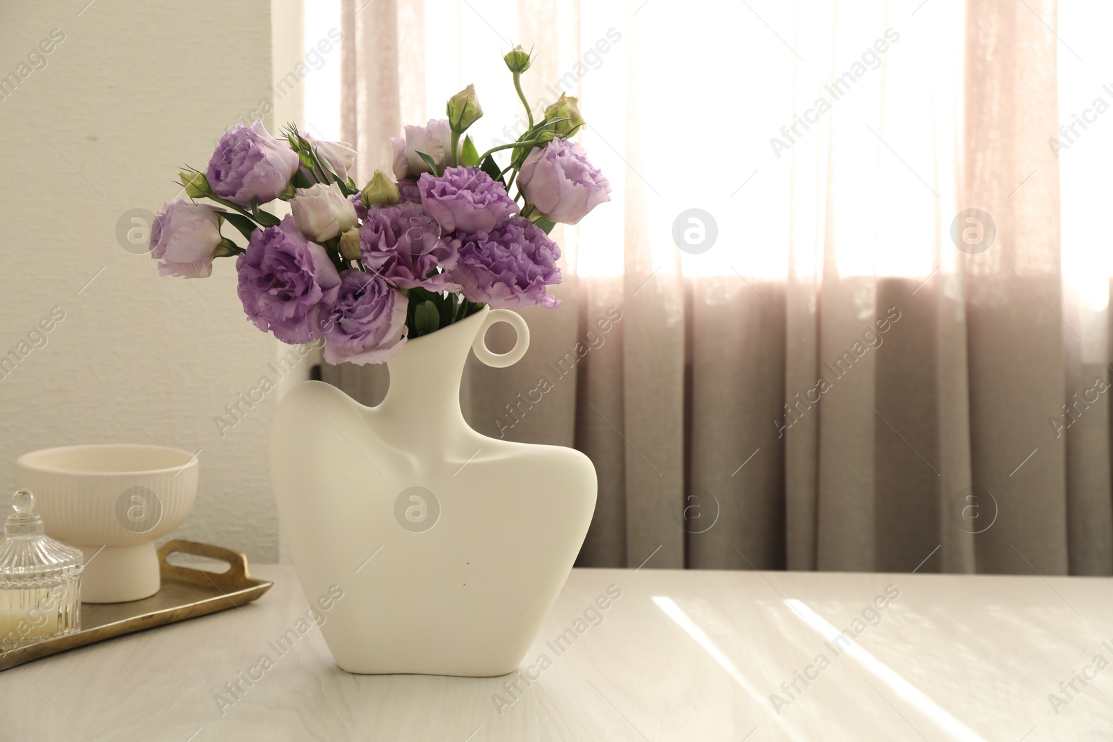 Photo of Stylish vase with beautiful flowers and decor on white wooden table at home, space for text