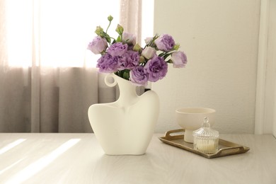 Photo of Stylish vase with beautiful flowers and decor on white wooden table at home