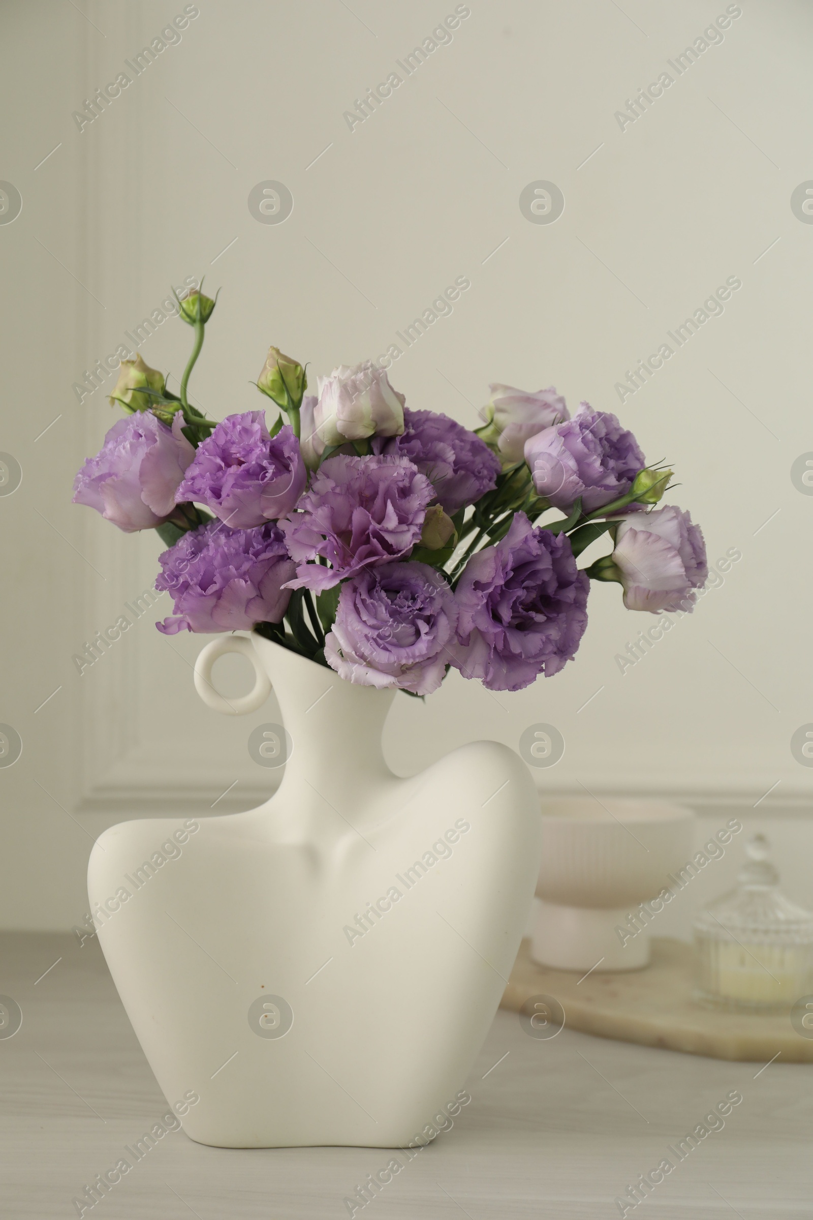 Photo of Stylish vase with beautiful flowers and decor on white wooden table at home