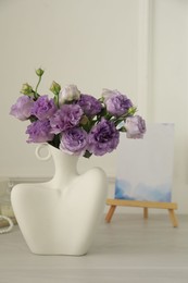 Photo of Stylish vase with beautiful flowers and decor on white wooden table at home