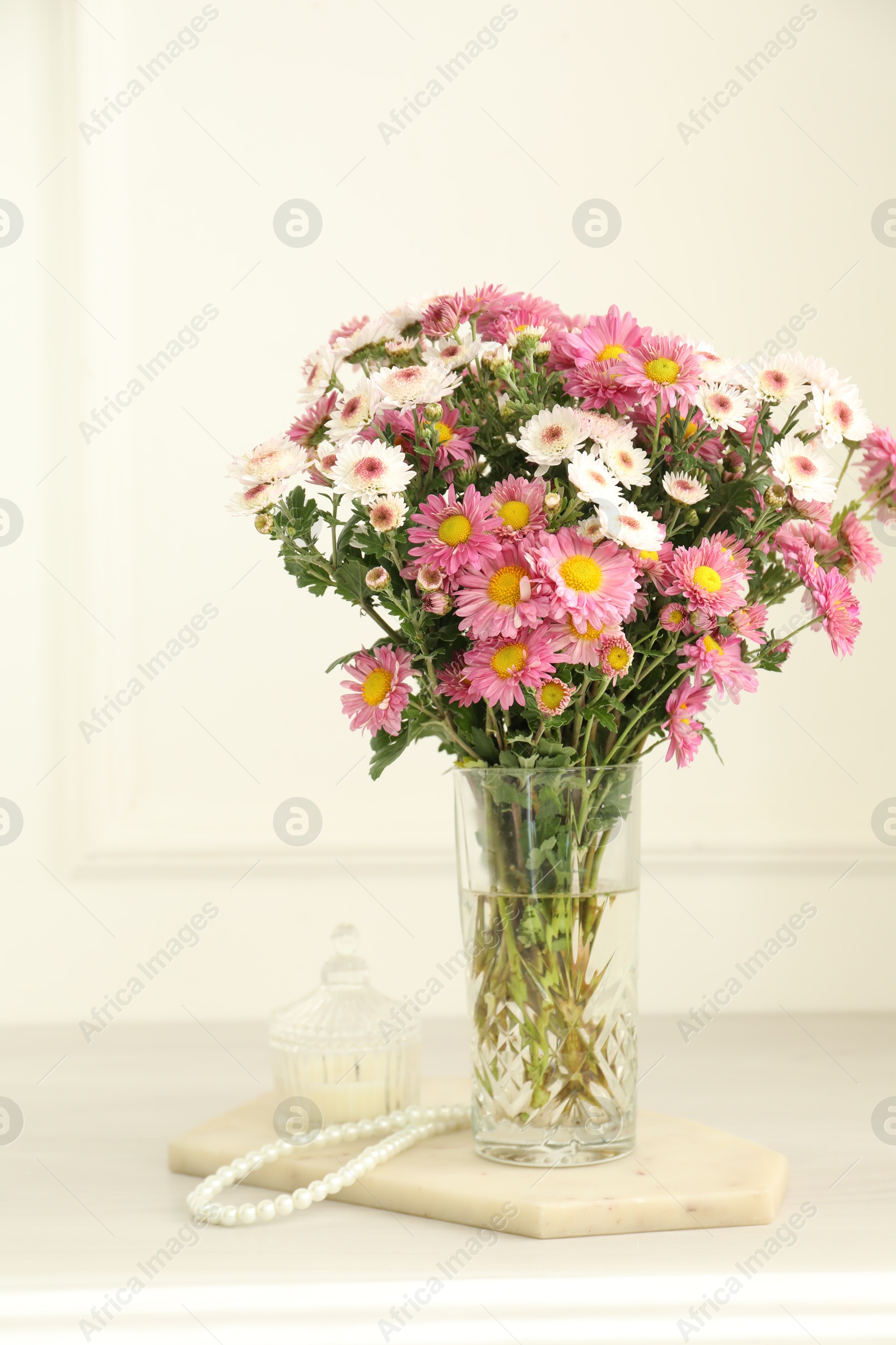 Photo of Beautiful flowers in glass vase and decor on white wooden table at home