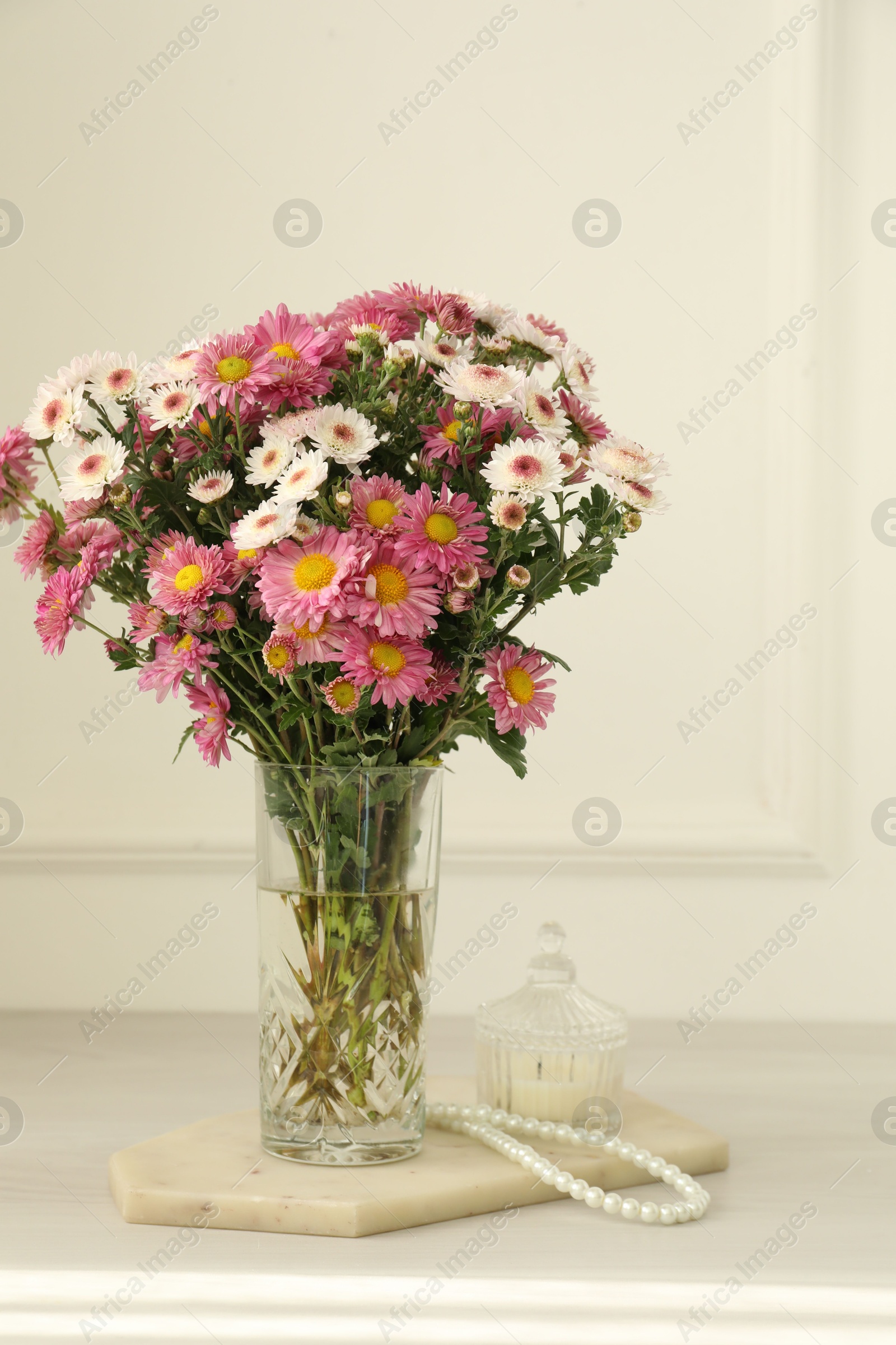 Photo of Beautiful flowers in glass vase and decor on white wooden table at home