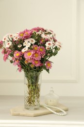 Photo of Beautiful flowers in glass vase and decor on white wooden table at home