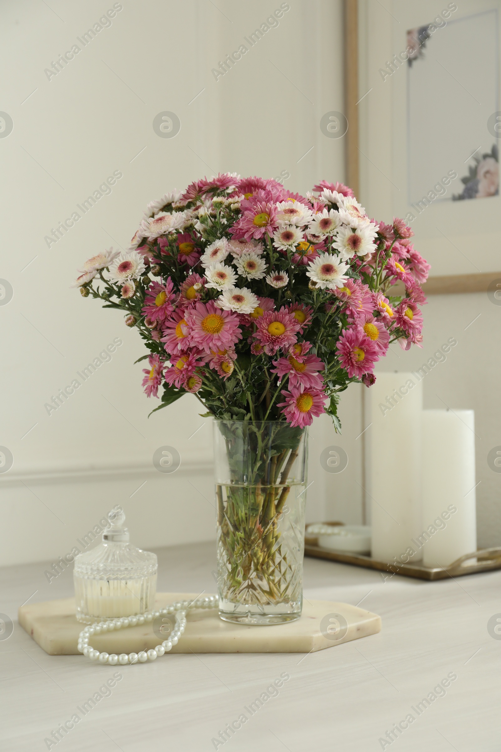 Photo of Beautiful flowers in glass vase and decor on white wooden table at home