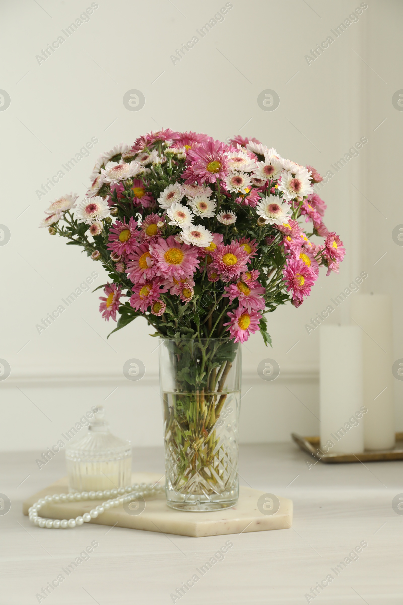 Photo of Beautiful flowers in glass vase and decor on white wooden table at home