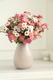 Beautiful flowers in vase on white table at home