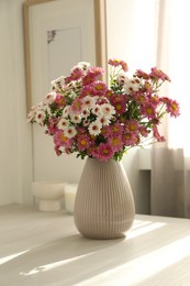 Photo of Beautiful flowers in vase and decor on white table at home