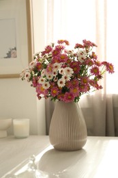 Beautiful flowers in vase and decor on white table at home