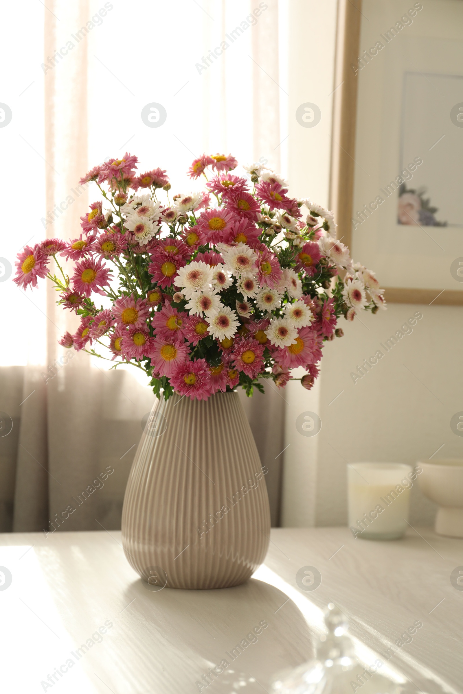 Photo of Beautiful flowers in vase and decor on white table at home