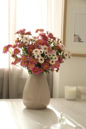 Photo of Beautiful flowers in vase and decor on white table at home