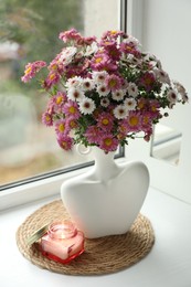 Photo of Stylish vase with beautiful flowers and burning candle near window at home