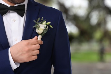 Image of Groom with boutonniere outdoors, closeup. Wedding accessory