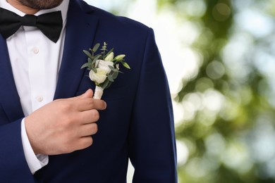 Image of Groom with boutonniere outdoors, closeup. Wedding accessory