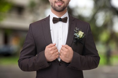 Image of Groom with boutonniere outdoors, closeup. Wedding accessory