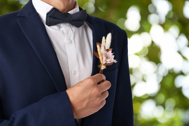 Image of Groom with boutonniere outdoors, closeup. Wedding accessory