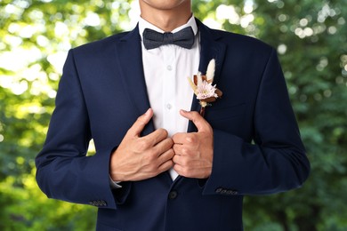 Image of Groom with boutonniere outdoors, closeup. Wedding accessory