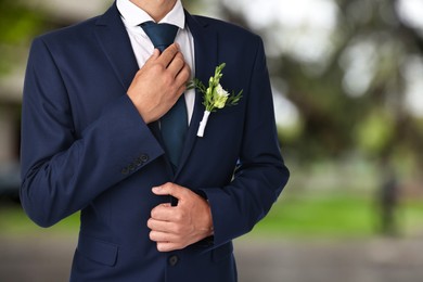 Image of Groom with boutonniere outdoors, closeup. Wedding accessory