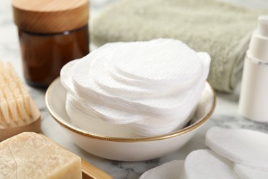 Photo of Cotton pads and beauty products on light table, closeup