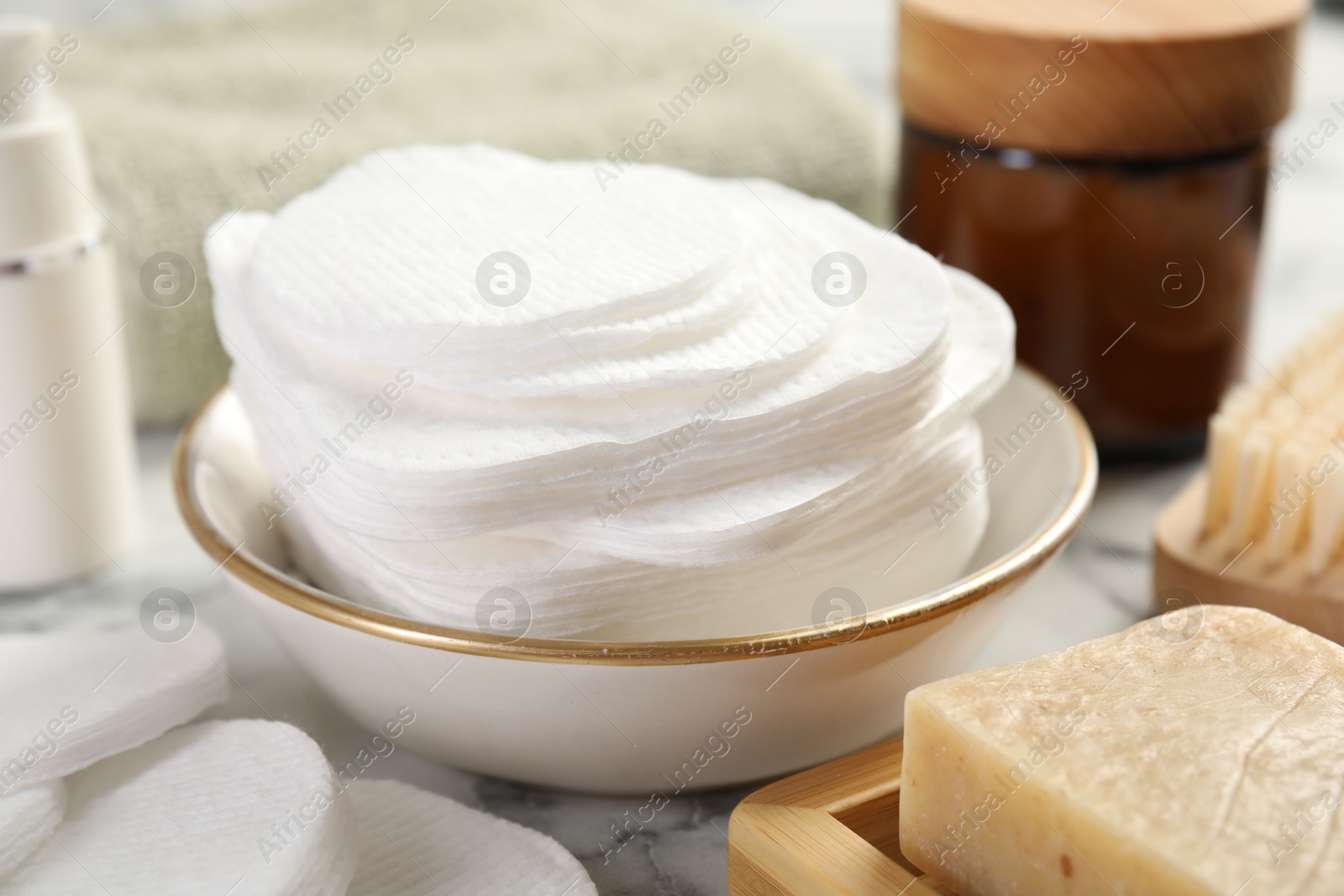 Photo of Cotton pads and beauty products on light table, closeup