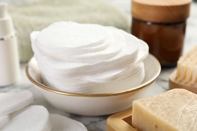 Photo of Cotton pads and beauty products on light table, closeup