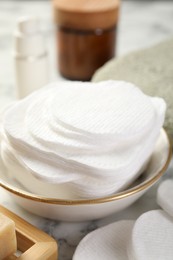 Photo of Cotton pads and beauty products on light table, closeup