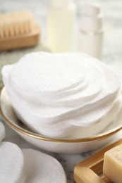 Photo of Cotton pads and beauty products on light table, closeup