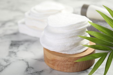 Photo of Cotton pads and palm leaf on light marble table, closeup