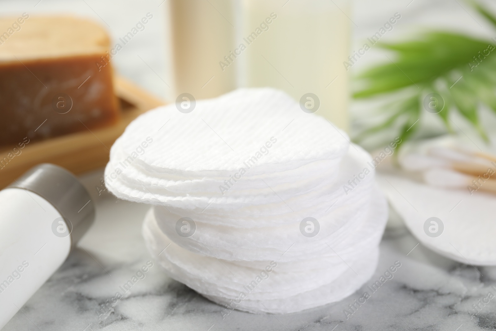 Photo of Cotton pads and cosmetic products on light marble table, closeup