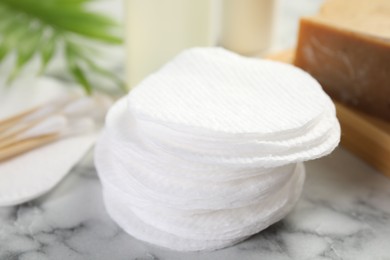 Photo of Cotton pads and cosmetic products on light marble table, closeup