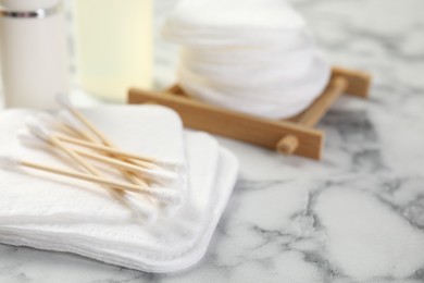 Photo of Cotton pads and swabs on light marble table, closeup