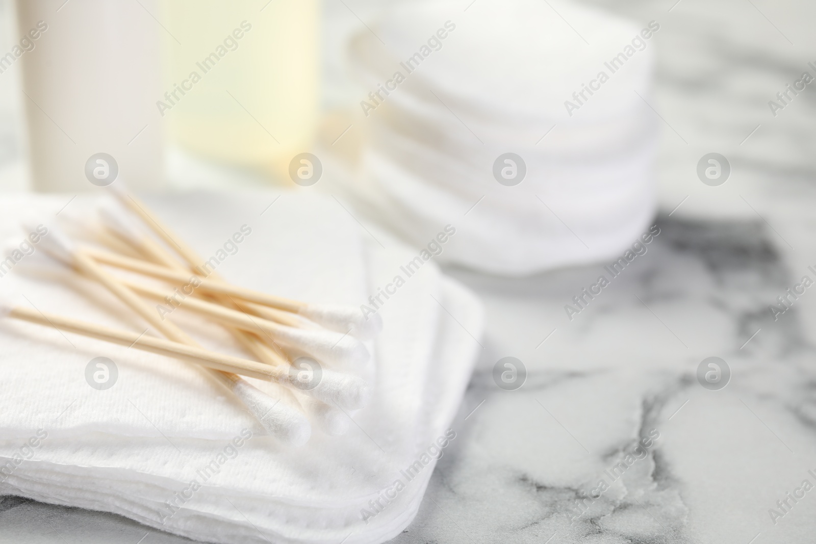 Photo of Cotton pads and swabs on light marble table, closeup