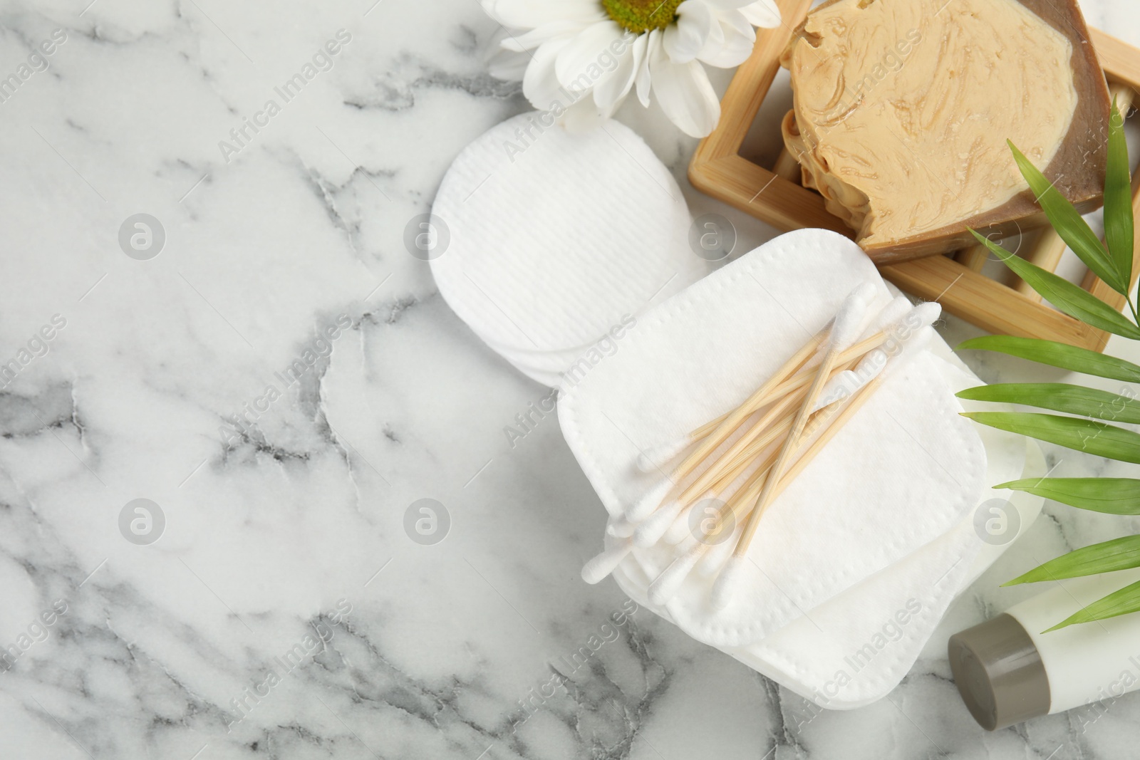 Photo of Flat lay composition with cotton pads on light marble table, space for text