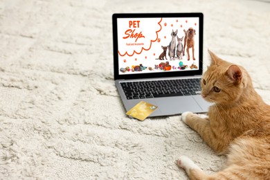 Image of Cute ginger cat near laptop with open online pet shop website on carpet