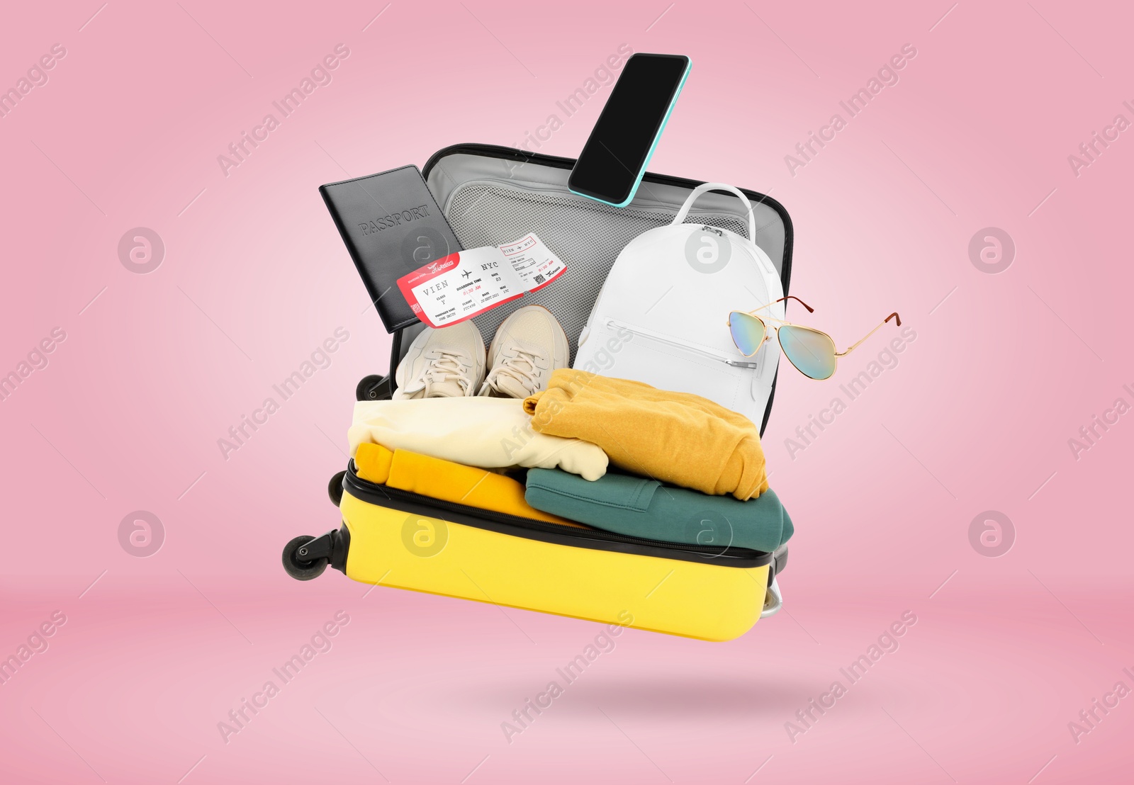 Image of Suitcase, clothes and other items in air on pink background. Ready to travel