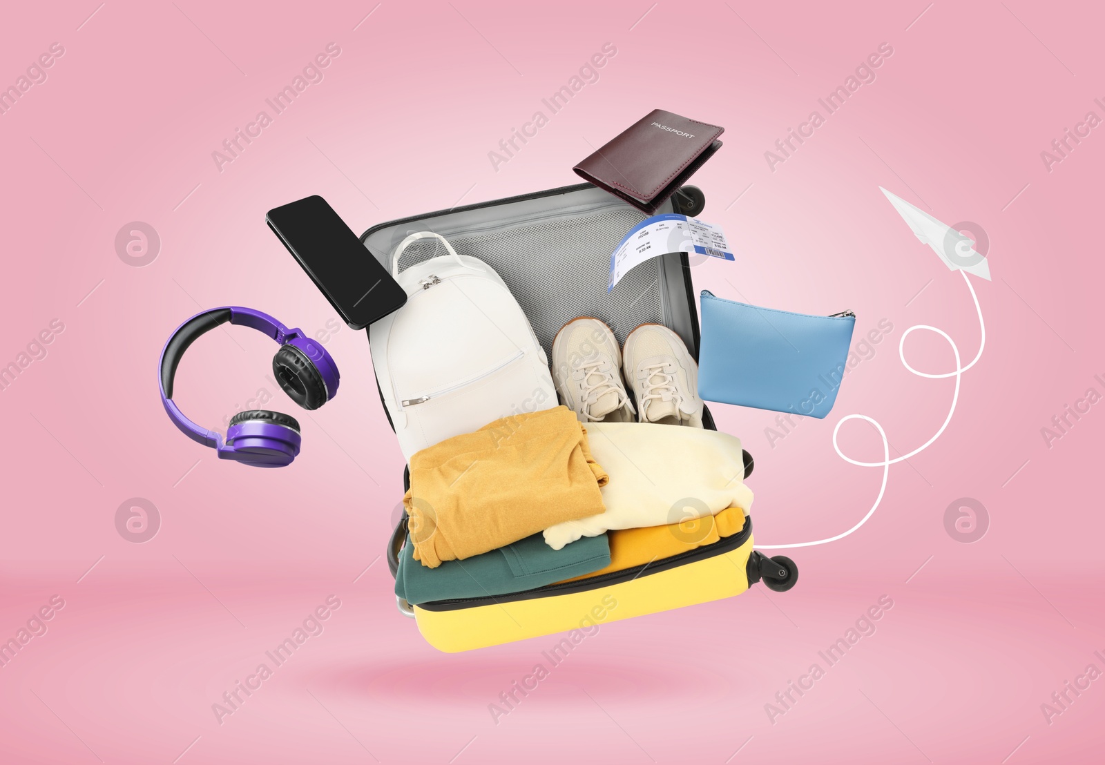 Image of Suitcase, clothes and other items in air on pink background. Ready to travel