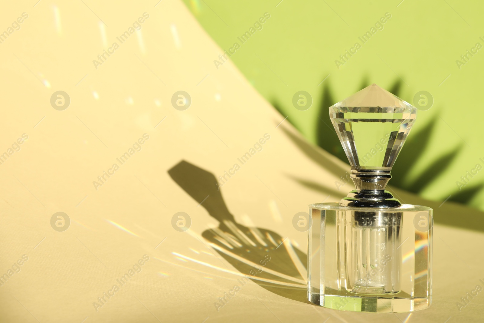 Photo of Beautiful perfume bottle on color background against shadow in shape of leaf. Space for text