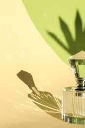 Photo of Beautiful perfume bottle on color background against shadow in shape of leaf