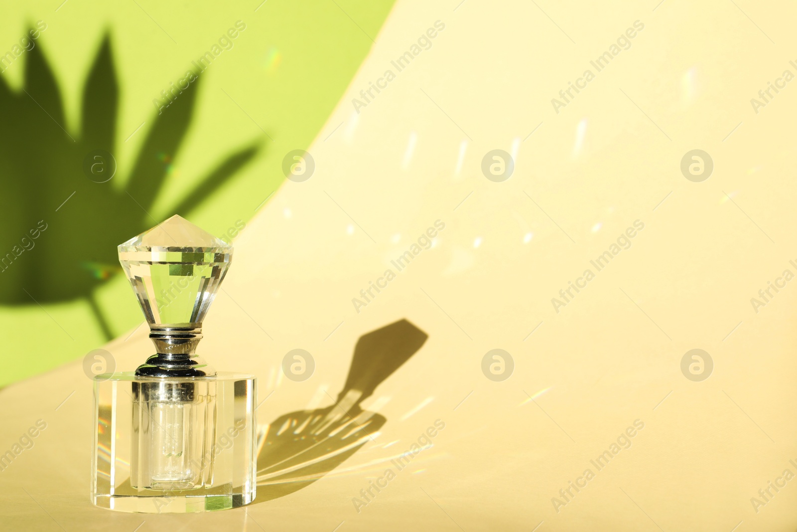 Photo of Beautiful perfume bottle on color background against shadow in shape of leaf. Space for text