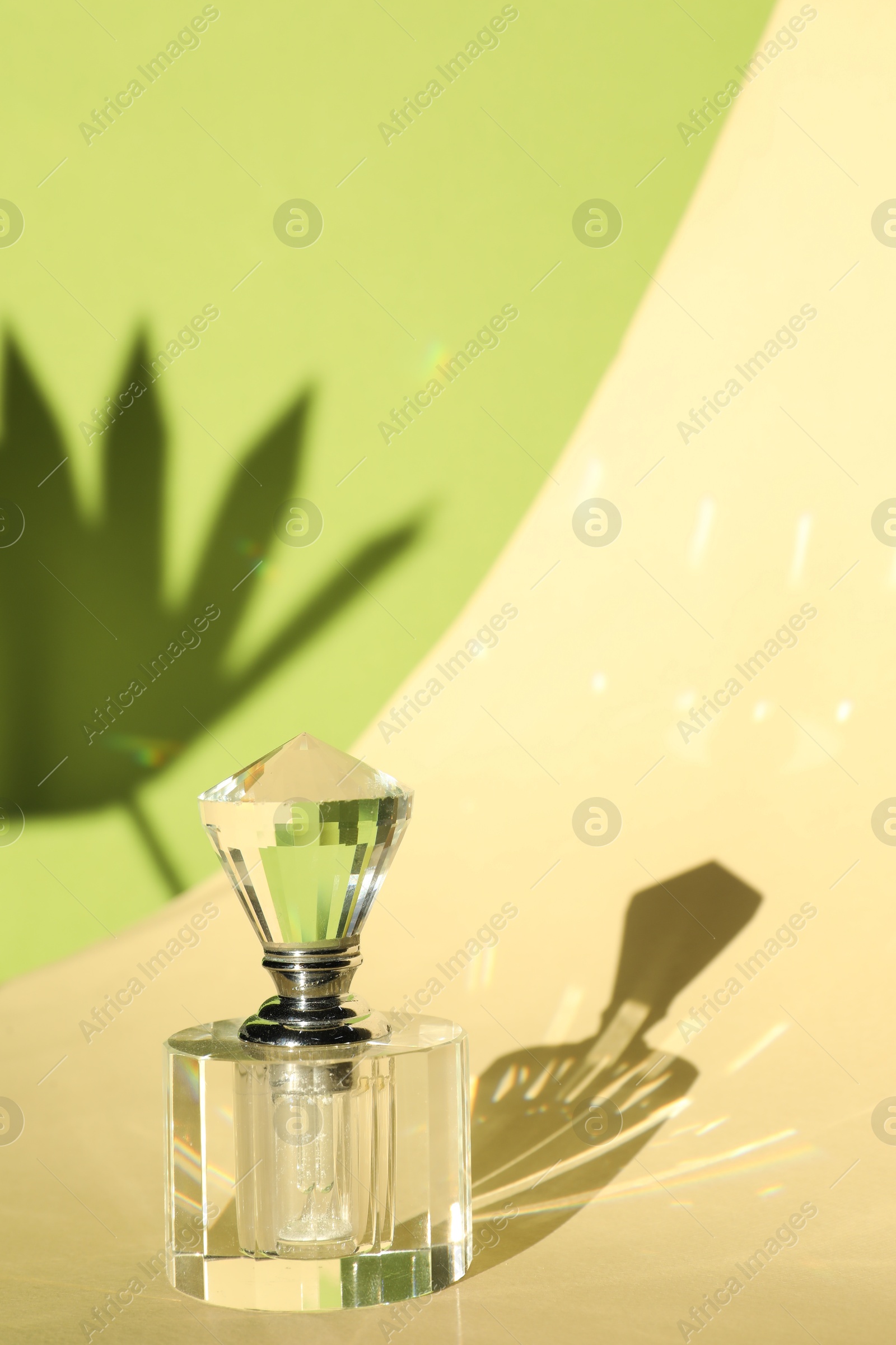 Photo of Beautiful perfume bottle on color background against shadow in shape of leaf