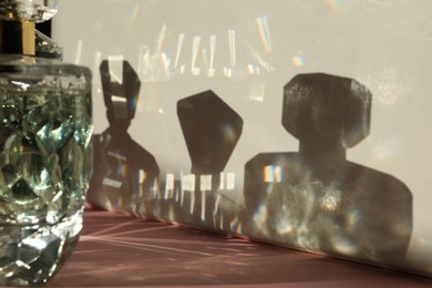 Photo of Perfume bottles casting shadows on light background