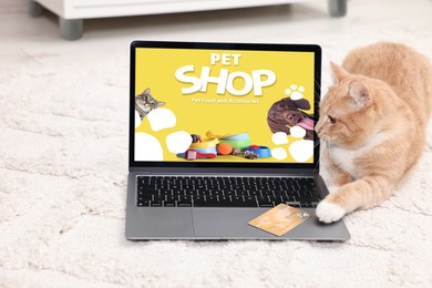 Image of Laptop with open online pet shop website. Cute ginger cat touching computer with paw at home